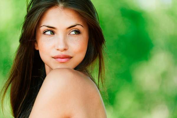 Young woman looking over shoulder wearing tank top outside.