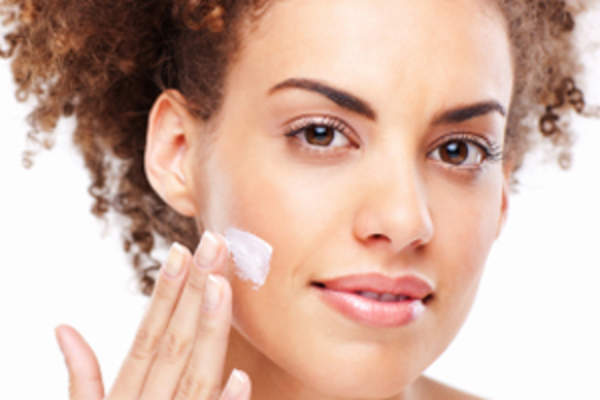 Young women applies lotion to her face.