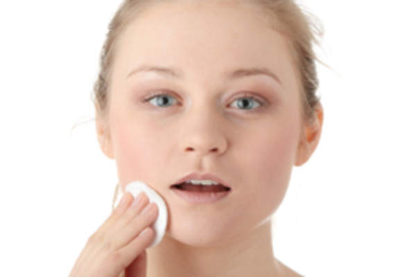 Young women removing makeup with cotton wipe.