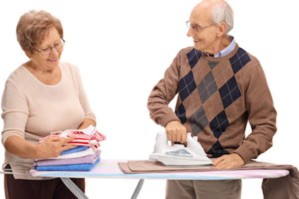 Happy older couple folding and ironing together.