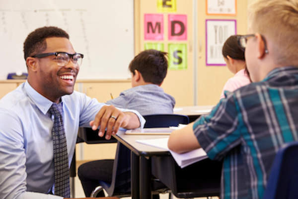 Male grade school teacher talking to student.