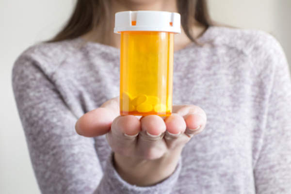 Woman holding up a prescription bottle