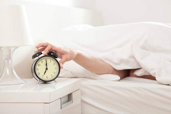 Woman turning off alarm clock.
