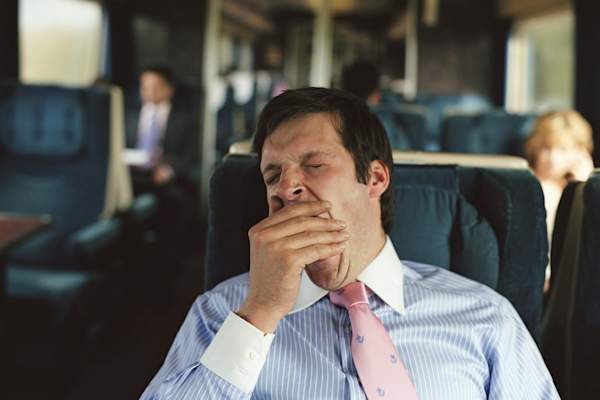 Business man yawning on train.