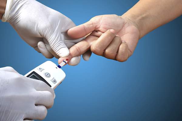 Doctor checking patient's blood glucose.