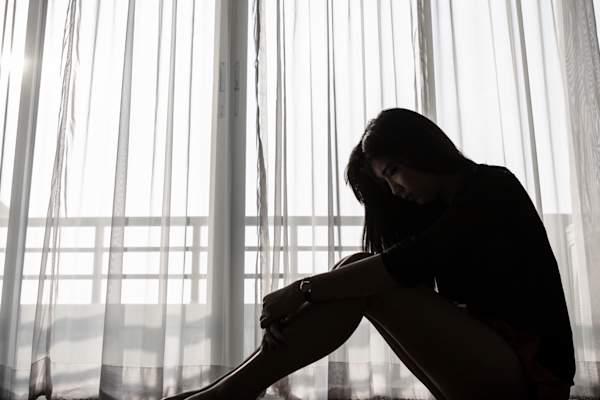 Depressed woman sitting on the floor of her home.