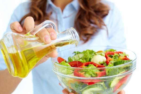 Putting olive oil on salad.