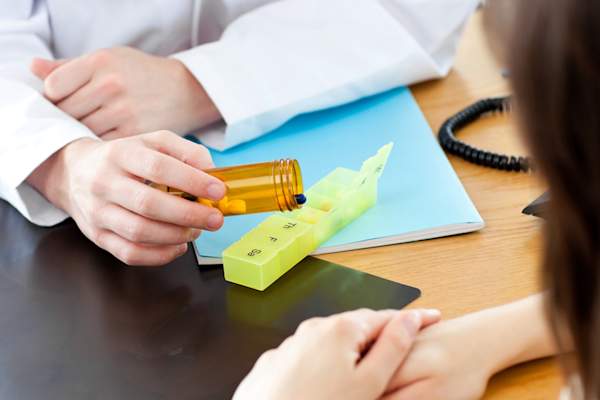 Doctor giving patient pill and explanation of medication.