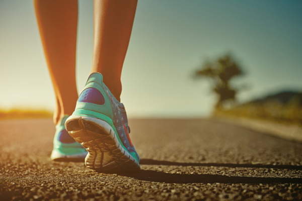 Woman walking in sneakers on road.