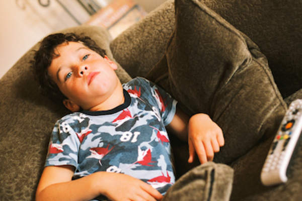 Bored kid watching television, on couch.