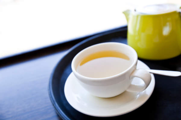 Cup of Green Tea on a tray with saucer and spoon.