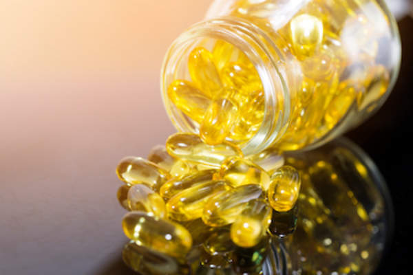 Bottle of omega-3 supplements spilling on to table.