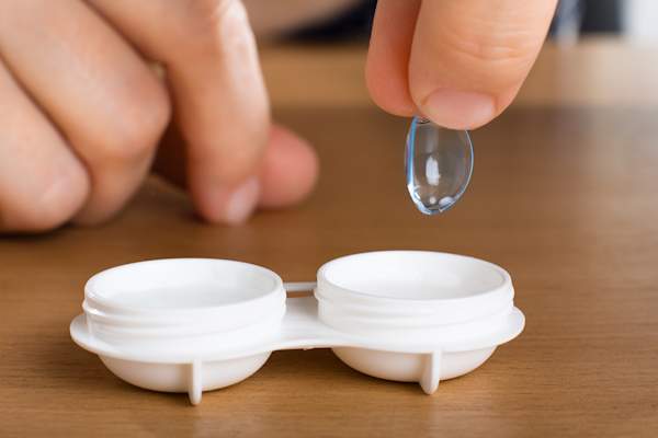 Putting a contact lens into a lens case.