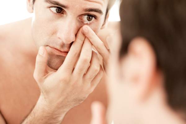 Man taking out a contact lens.