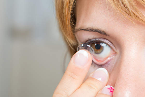 Young woman putting in a contact lens.