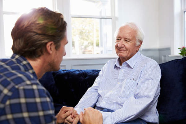 Adult son comforting senior father.