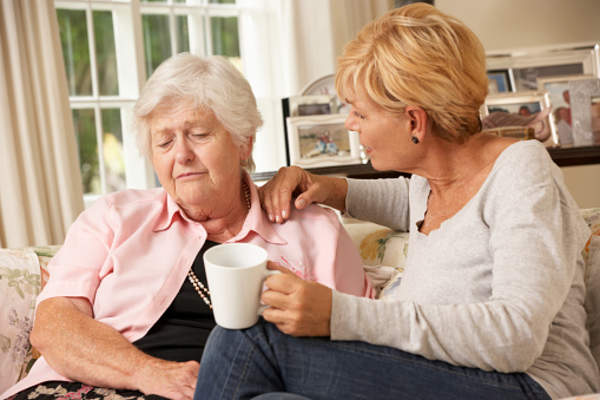 Adult daughter supporting senior mother at home.