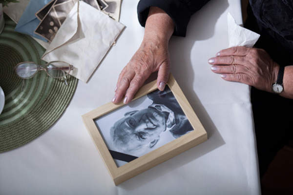 Elderly woman mourning the loss of her husband looking at his picture.