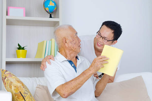 Elderly father showing adult son a book he is reading.