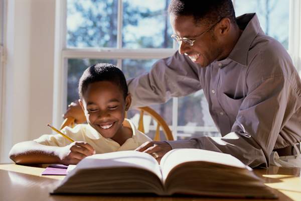 Happy father and young daughter doing homework.