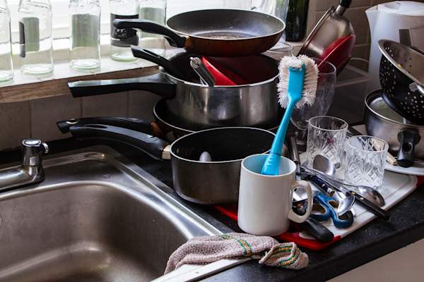 Pile of dirty dishes in sink.