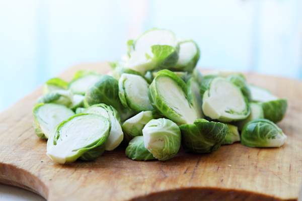 Pile of halved brussels sprouts on chopping board.