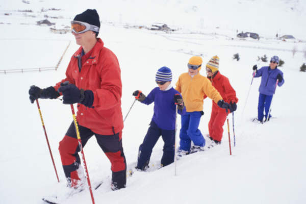 Family walking through the snow in winter gear.