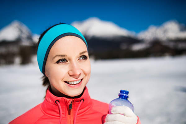 Woman holding water bottle outside in the winter.