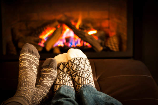Couple cuddling in front of a fireplace.
