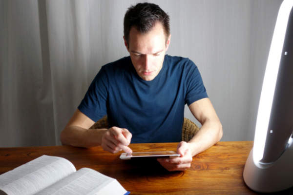 Man working on tablet and reading book late at night.