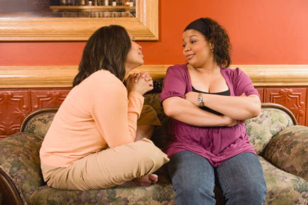 Adult women talking at home on the couch.