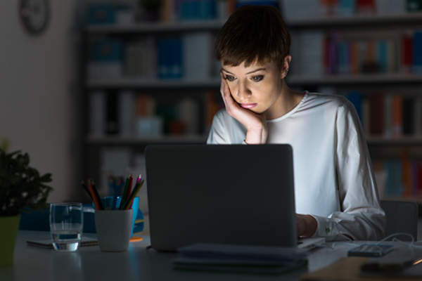 Young woman on laptop in library at night.