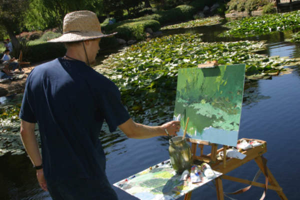 Man painting picture outside.