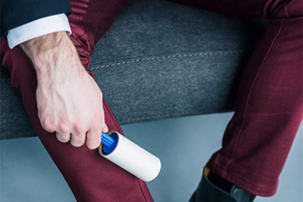 Man using lint roller on pants.