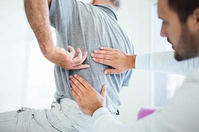Doctor assessing patient's back pain.