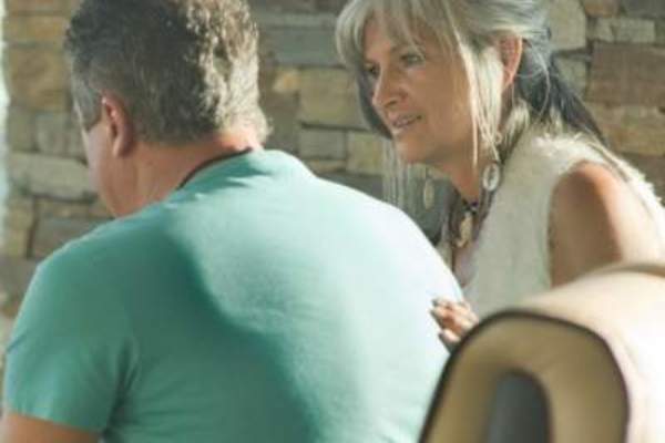 Couple talking on bench outside.