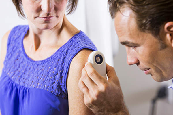 Dermatologist examining patient with a dermascope.