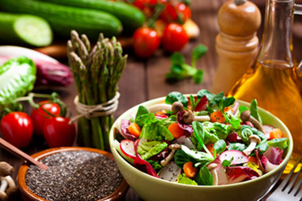 Healthy salad with vegetables and oil in the background.