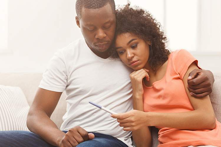 Disappointed couple holding negative pregnancy test.