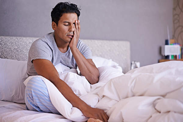 Man waking up with a headache as a side effect of melatonin.