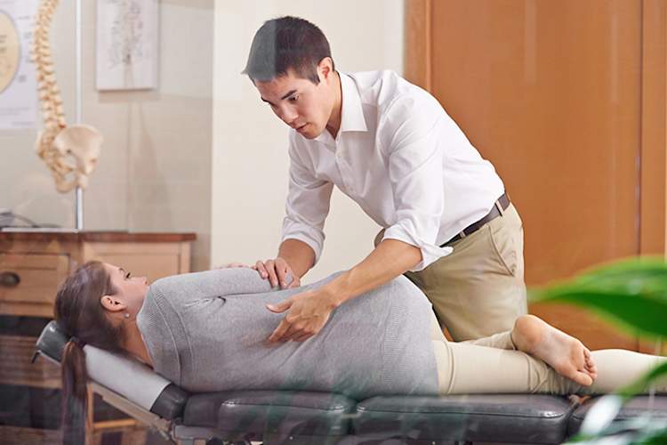 Chiropractor examining a woman's spine.