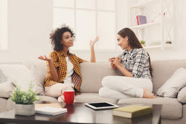 two friends chatting in living room over coffees