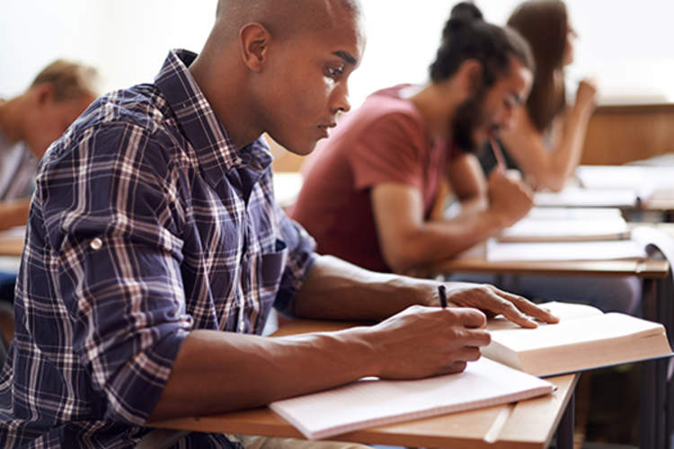 College student taking notes in class.