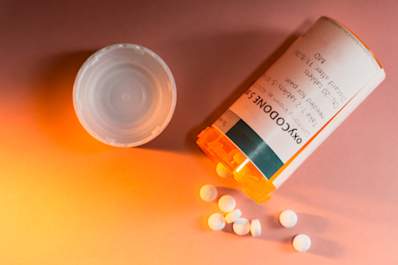 Oxycodone prescription spilling from container on table.