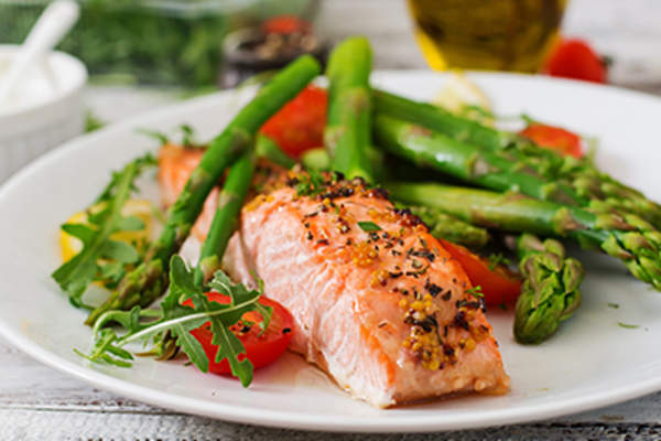 Baked salmon garnished with asparagus and tomatoes with herbs.
