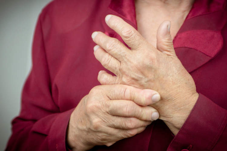 Older lady rubbing arthritic hands.