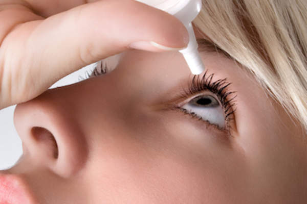 Woman using lubricating eye drops.
