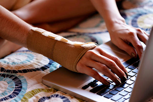 Woman with a wrist splint using a laptop.