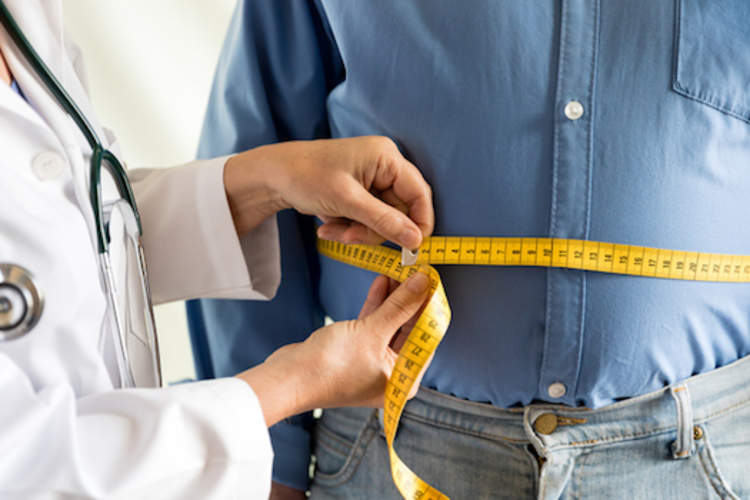 Doctor measuring waist of overweight man.