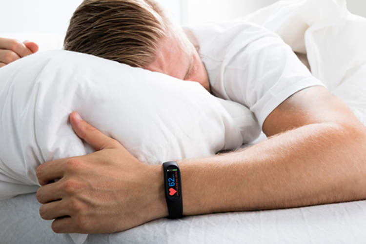Man sleeping while wearing fitness tracker on wrist.